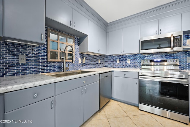 kitchen featuring light tile patterned floors, tasteful backsplash, a sink, appliances with stainless steel finishes, and light countertops