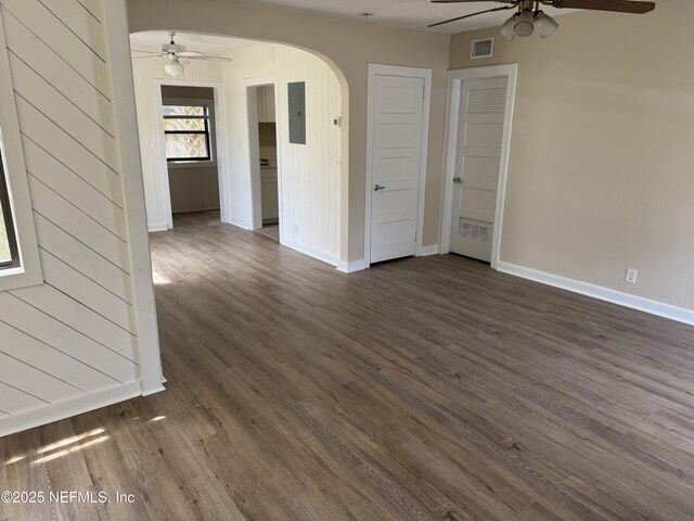 spare room featuring visible vents, electric panel, arched walkways, dark wood-type flooring, and a ceiling fan