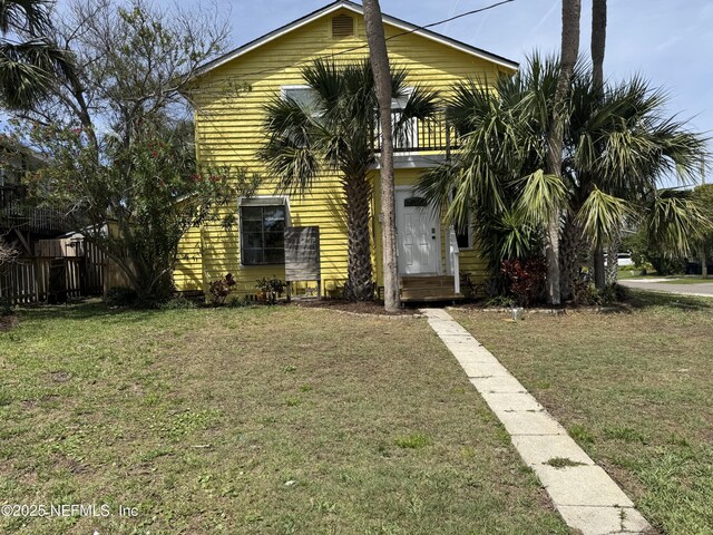 view of property hidden behind natural elements with fence and a front yard