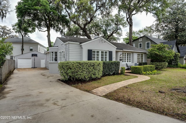 view of front facade featuring an outdoor structure, concrete driveway, stucco siding, a front lawn, and a garage