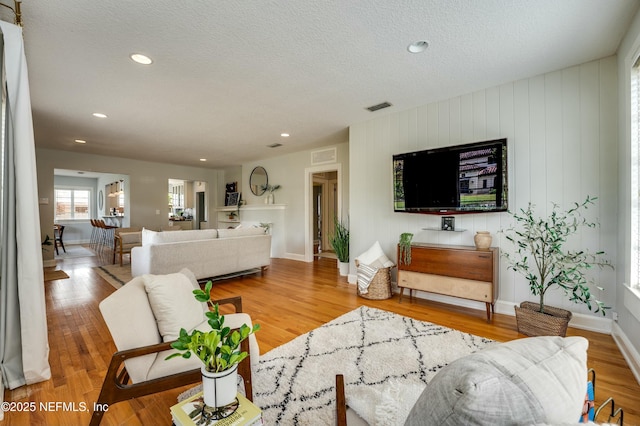 living area with recessed lighting, visible vents, and wood finished floors