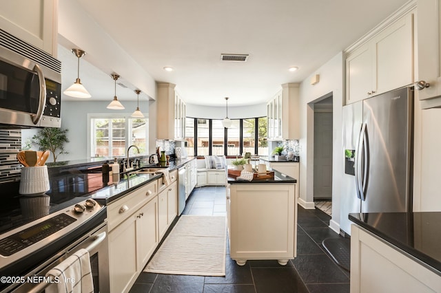 kitchen with appliances with stainless steel finishes, dark countertops, tasteful backsplash, and visible vents