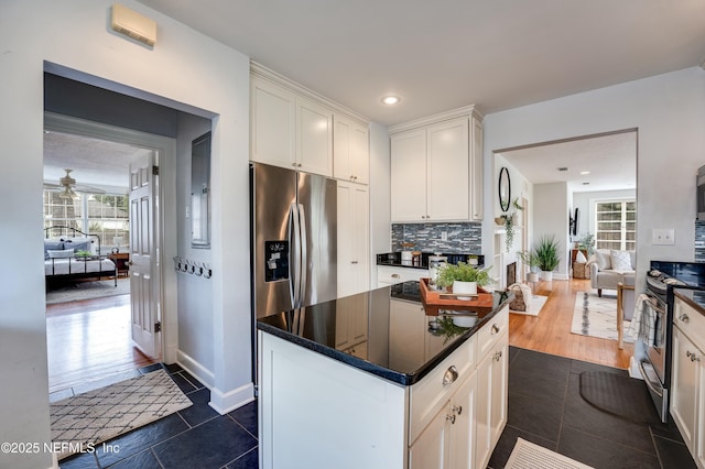 kitchen featuring appliances with stainless steel finishes, open floor plan, white cabinetry, and backsplash