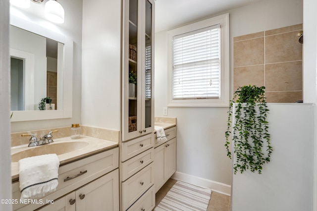 full bath featuring tile patterned floors, vanity, baseboards, and tiled shower