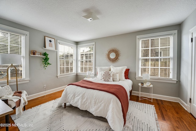 bedroom with a textured ceiling, wood finished floors, and baseboards