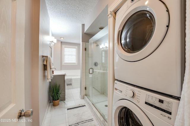 laundry room with a textured ceiling, stacked washer and clothes dryer, and laundry area