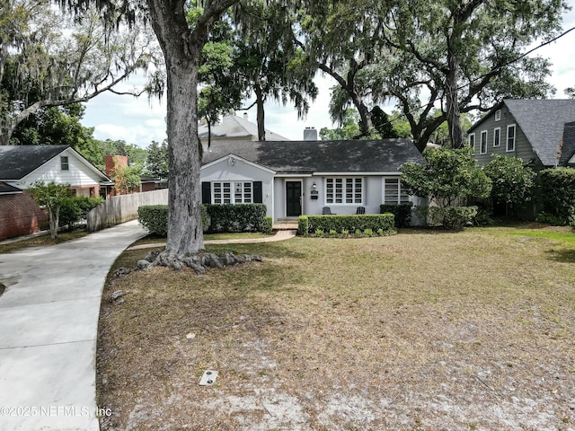 single story home featuring a front yard, driveway, roof with shingles, and fence