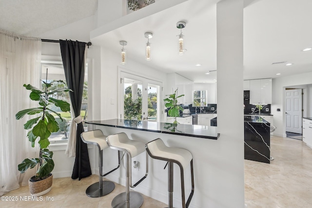 116 Lost Beach Ln, Ponte Vedra Beach, FL 32082 - kitchen featuring dark countertops, a sink, a kitchen breakfast bar, white cabinetry, and light tile patterned floors