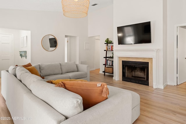 1625 Panther Ridge Ct, Jacksonville, FL 32225 - living area with a fireplace with flush hearth, light wood-type flooring, visible vents, baseboards, and a towering ceiling