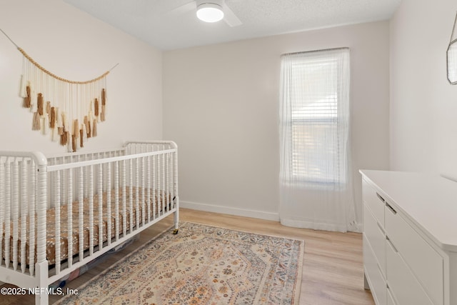 1625 Panther Ridge Ct, Jacksonville, FL 32225 - bedroom with light wood-style floors, ceiling fan, baseboards, and a crib