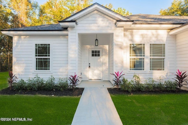 exterior space featuring a shingled roof and a front yard