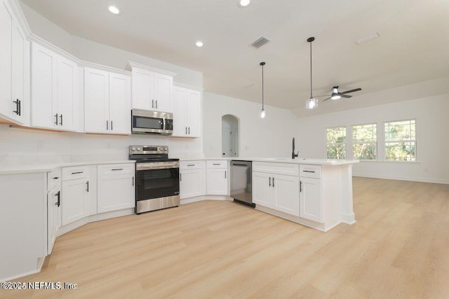kitchen featuring light wood finished floors, arched walkways, a peninsula, appliances with stainless steel finishes, and ceiling fan