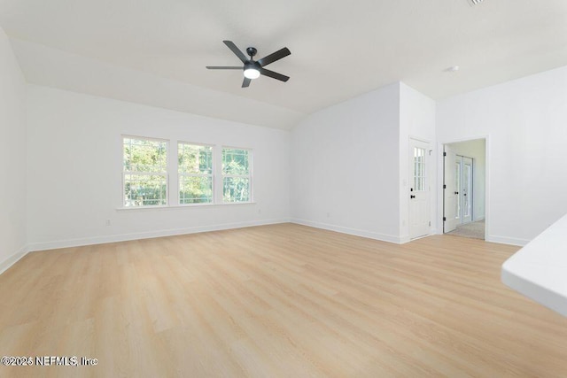 spare room with vaulted ceiling, light wood finished floors, baseboards, and ceiling fan