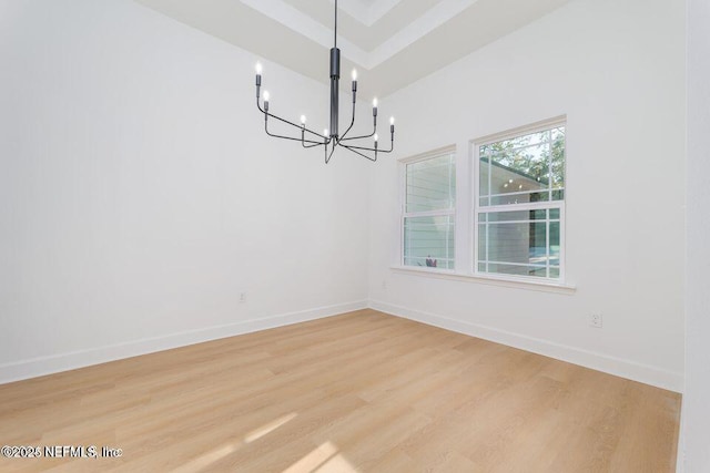 unfurnished dining area with light wood-style flooring, baseboards, and an inviting chandelier