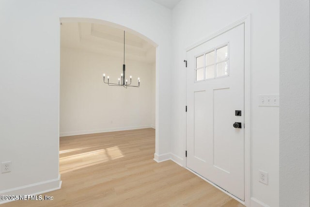 foyer featuring baseboards, an inviting chandelier, and light wood-type flooring