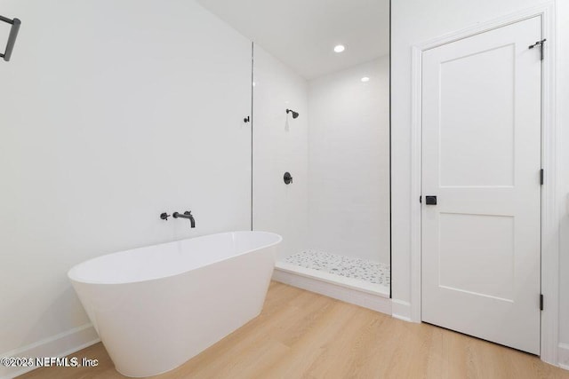 full bathroom featuring recessed lighting, a tile shower, wood finished floors, baseboards, and a soaking tub