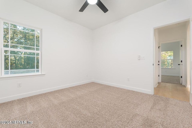 spare room featuring light carpet, a ceiling fan, and baseboards