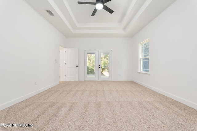 carpeted spare room with ceiling fan, baseboards, visible vents, and a raised ceiling
