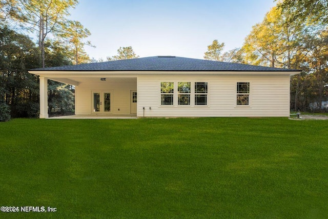back of house with a lawn, french doors, a patio area, and roof with shingles