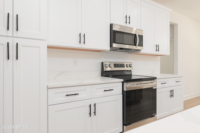295 SE 57th St, Keystone Heights, FL 32656 - kitchen with appliances with stainless steel finishes, white cabinetry, and light stone countertops