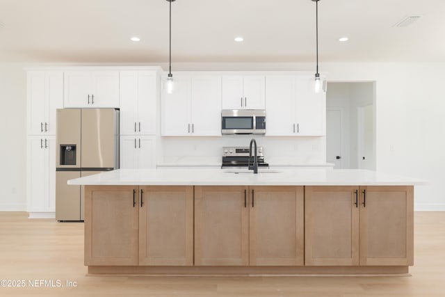 295 SE 57th St, Keystone Heights, FL 32656 - kitchen featuring stainless steel microwave, refrigerator with ice dispenser, a sink, light wood-type flooring, and an island with sink