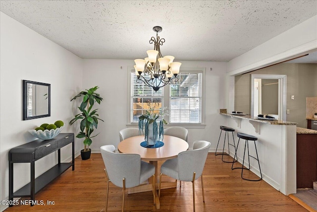 4379 San Jose Blvd, Jacksonville, FL 32207 - dining space with a chandelier, wood finished floors, baseboards, and a textured ceiling