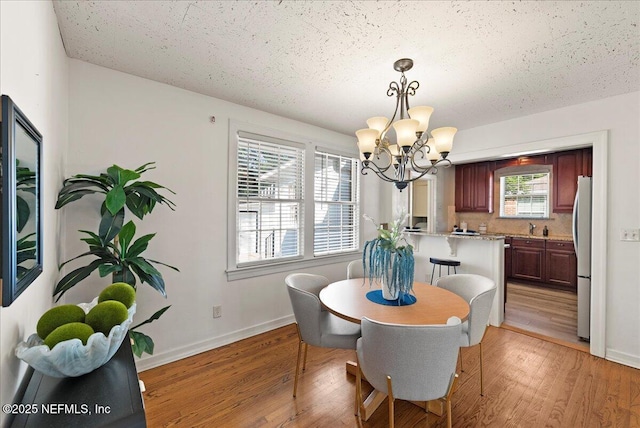 4379 San Jose Blvd, Jacksonville, FL 32207 - dining area featuring a chandelier, light wood-style floors, baseboards, and a textured ceiling
