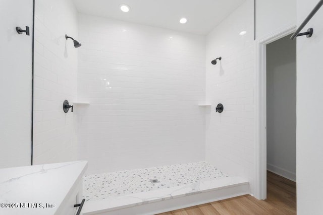 full bathroom with wood finished floors, recessed lighting, and a tile shower