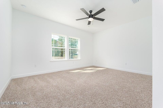 carpeted empty room with baseboards, a ceiling fan, and visible vents