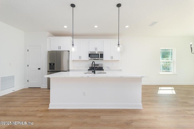 kitchen with stainless steel appliances, a kitchen island with sink, visible vents, white cabinetry, and light wood-style floors