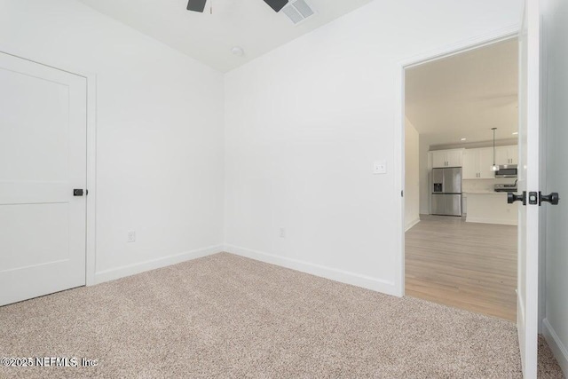 unfurnished room featuring visible vents, a ceiling fan, baseboards, and light carpet