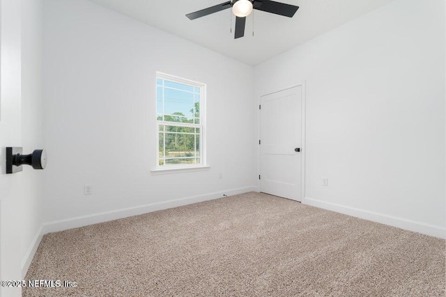 carpeted spare room featuring a ceiling fan and baseboards