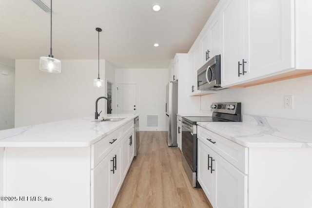 kitchen featuring a sink, an island with sink, appliances with stainless steel finishes, light wood finished floors, and white cabinetry
