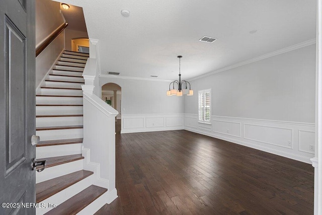 foyer entrance with arched walkways, a chandelier, crown molding, stairway, and wood finished floors