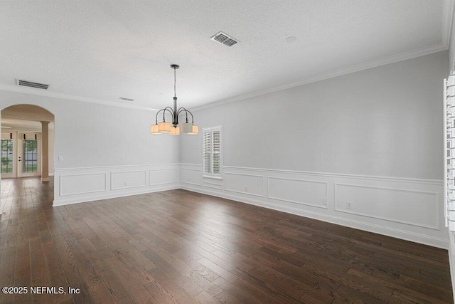 unfurnished dining area with arched walkways, a chandelier, plenty of natural light, dark wood-type flooring, and wainscoting