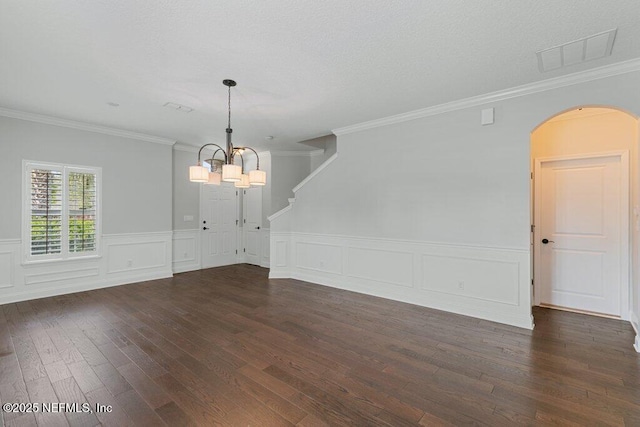 unfurnished dining area featuring arched walkways, dark wood-type flooring, a chandelier, wainscoting, and crown molding