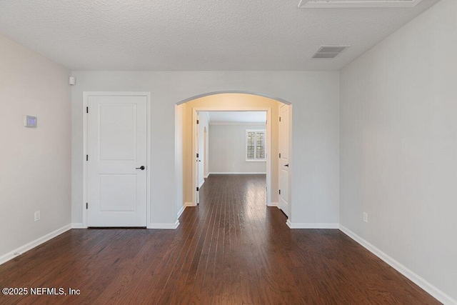 unfurnished room featuring arched walkways, wood finished floors, baseboards, and a textured ceiling
