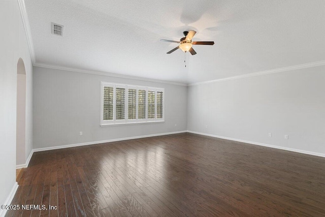empty room featuring arched walkways, a ceiling fan, dark wood-style flooring, crown molding, and baseboards