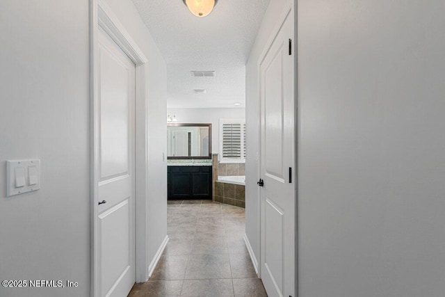 hallway featuring tile patterned floors and a textured ceiling