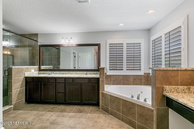 bathroom featuring a shower stall, a garden tub, double vanity, tile patterned flooring, and a textured ceiling