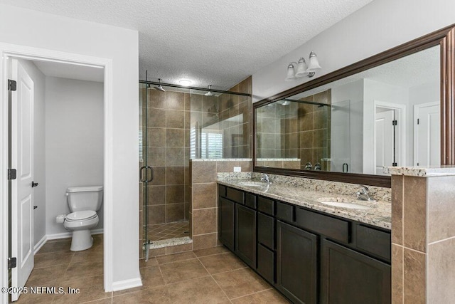 bathroom with a textured ceiling, tile patterned flooring, a stall shower, toilet, and double vanity