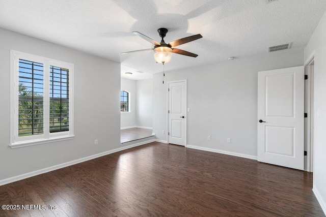 empty room with dark wood-style floors, a ceiling fan, baseboards, and a textured ceiling