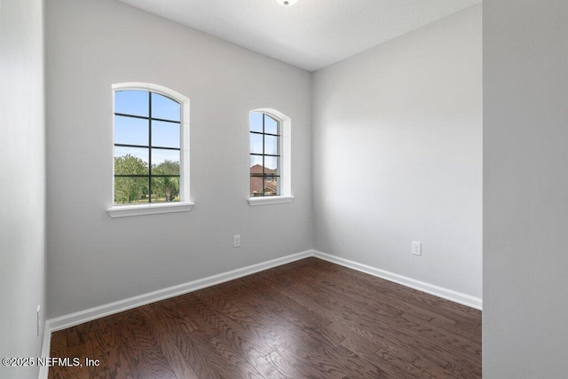 empty room featuring dark wood finished floors and baseboards