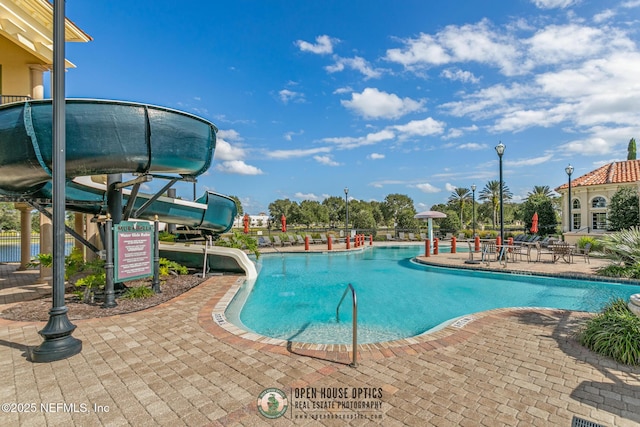 community pool with a patio and a water slide