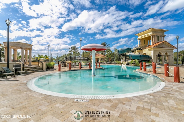 community pool featuring a water slide and a patio