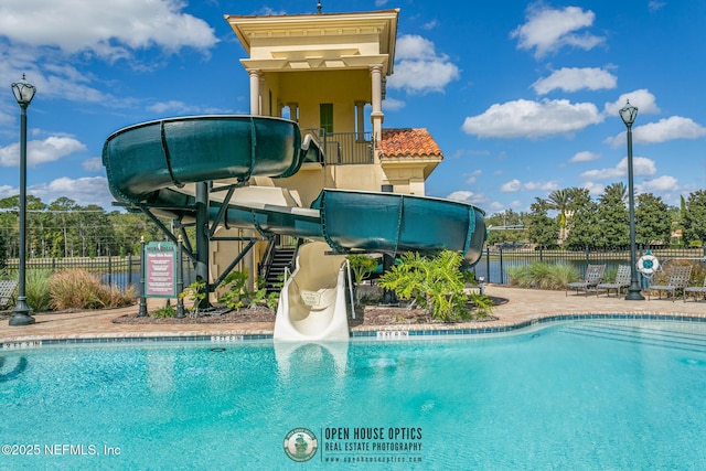 community pool featuring a water slide and fence