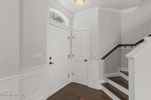 foyer entrance featuring dark wood-type flooring, crown molding, and stairway