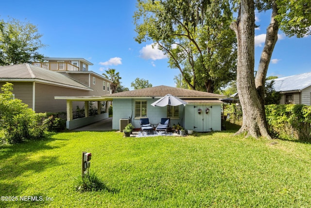back of property with a patio, an outbuilding, a lawn, concrete block siding, and a storage unit