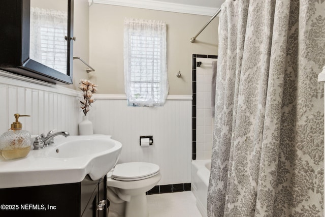 full bathroom featuring tile patterned floors, wainscoting, ornamental molding, toilet, and vanity