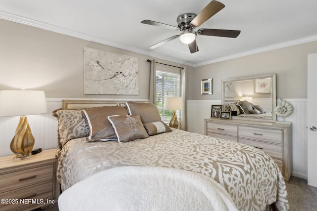 carpeted bedroom with crown molding, a ceiling fan, and wainscoting